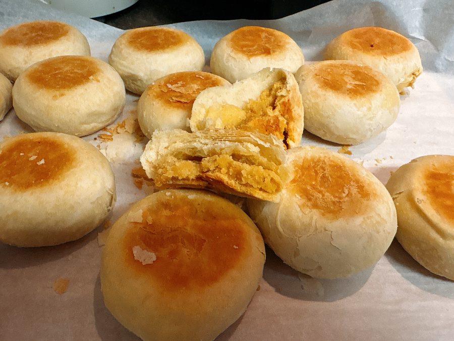 Golden flaky pastries on parchment, one broken open to show the filling